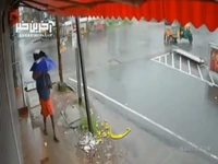 رد شدن اتوبوس از روی یک موتورسوار در خیابانی خیس و بارانی