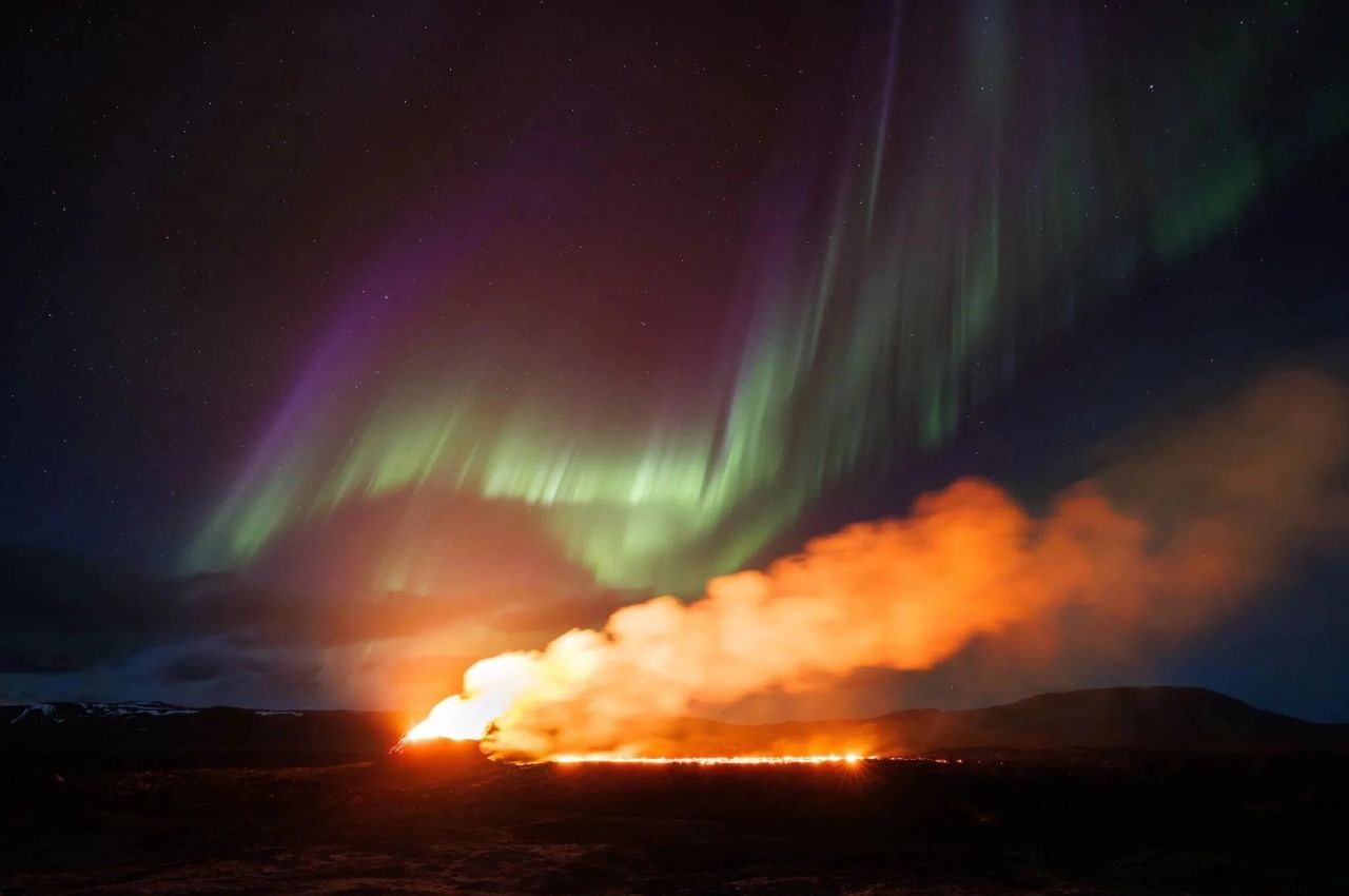 شفقِ قطبی در پس‌زمینه‌ی فورانِ آتشفشانی در ایسلند