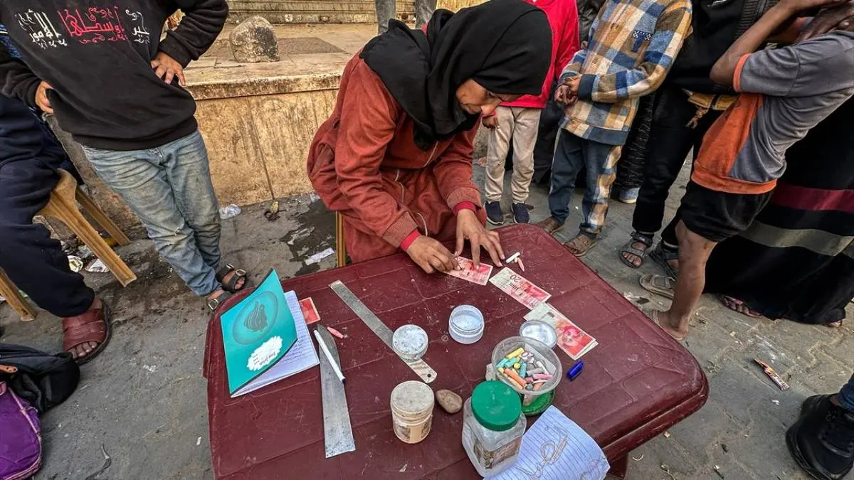 تصاویر زن فلسطینی که با ترمیم اسکناس‌های پاره امرار معاش می‌کند!