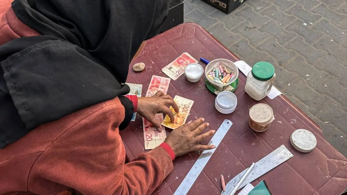 تصاویر زن فلسطینی که با ترمیم اسکناس‌های پاره امرار معاش می‌کند!