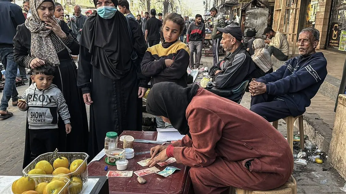 تصاویر زن فلسطینی که با ترمیم اسکناس‌های پاره امرار معاش می‌کند!