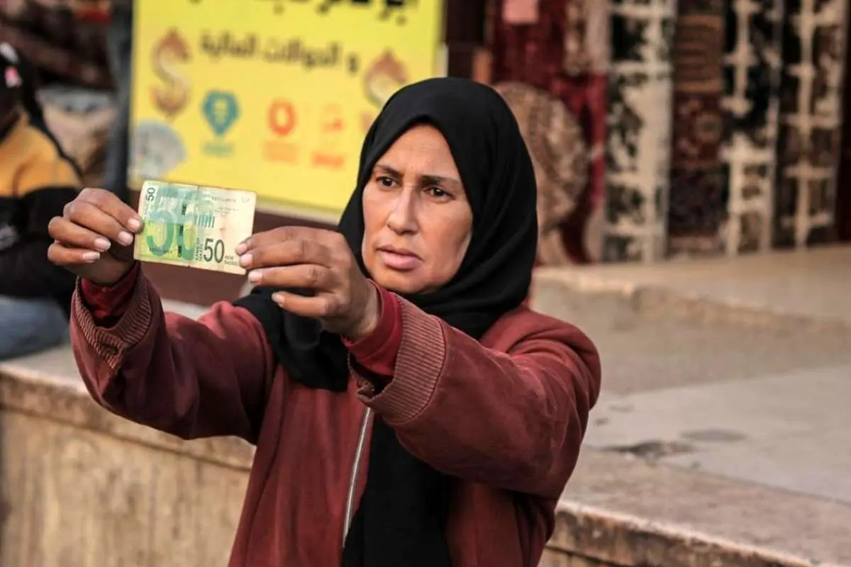 تصاویر زن فلسطینی که با ترمیم اسکناس‌های پاره امرار معاش می‌کند!