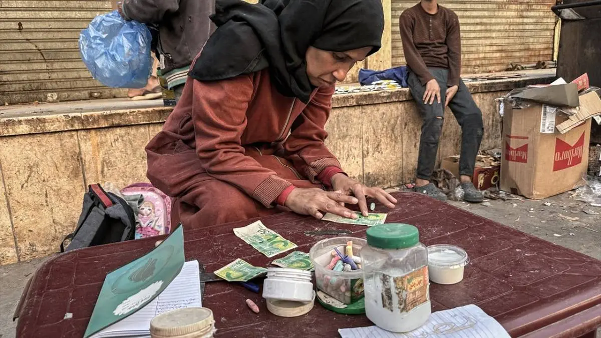 تصاویر زن فلسطینی که با ترمیم اسکناس‌های پاره امرار معاش می‌کند!