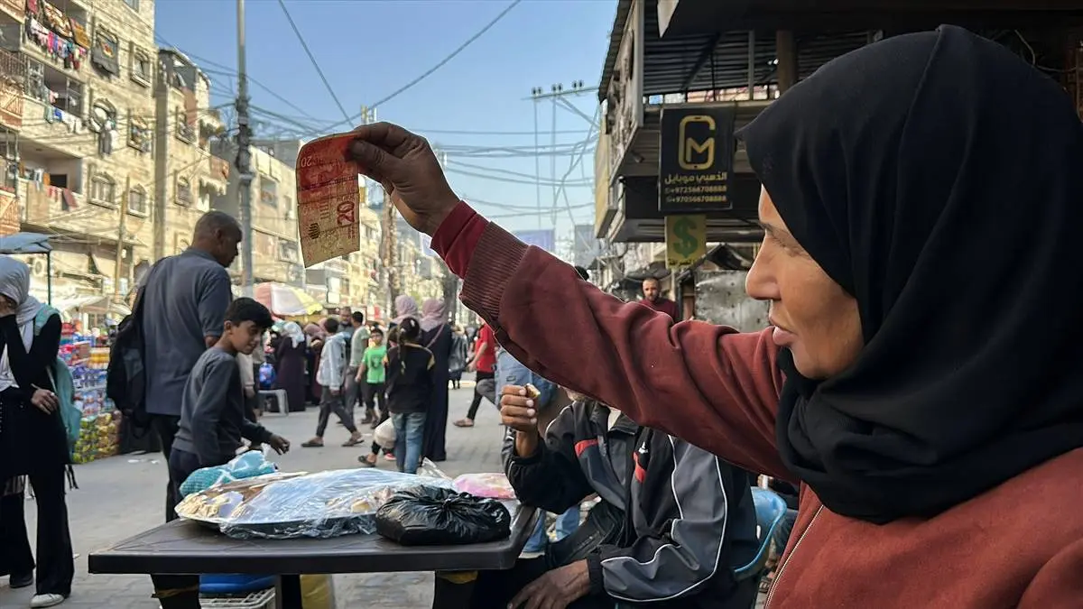 تصاویر زن فلسطینی که با ترمیم اسکناس‌های پاره امرار معاش می‌کند!